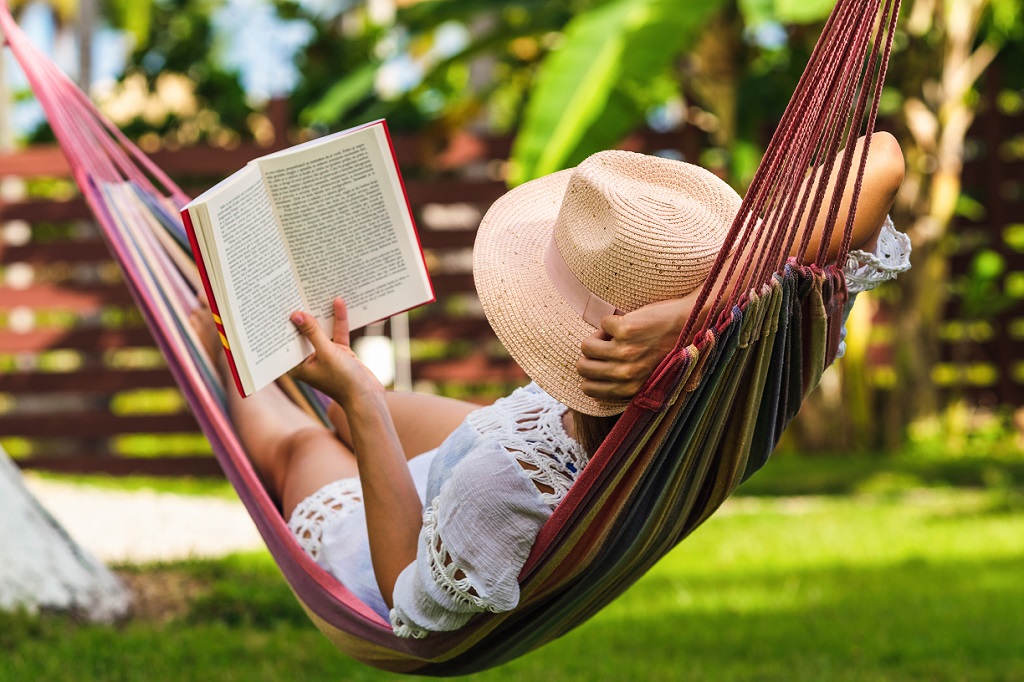 Woman reading book in hammock in tropical garden